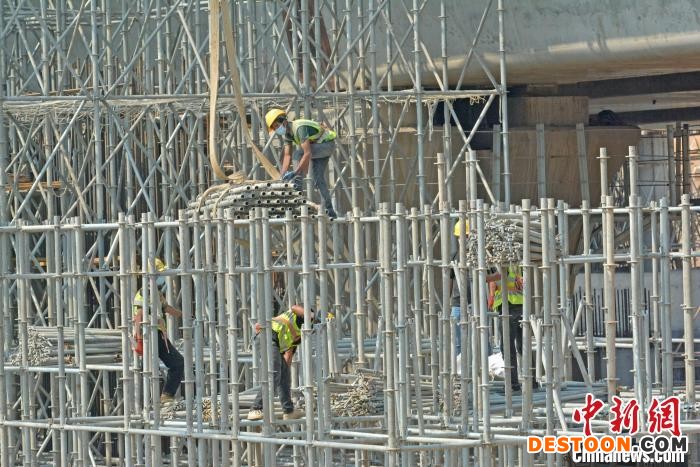 工人在装吊脚手架构件。 林弘梫 摄