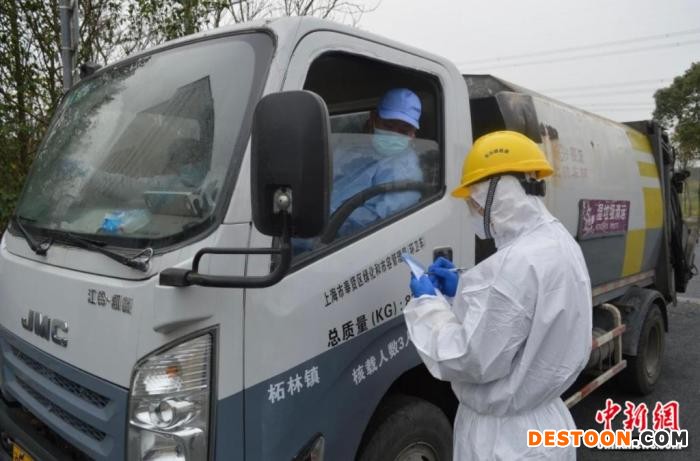 身穿防护的工作人员正在为进入厂区的垃圾清运车登记。