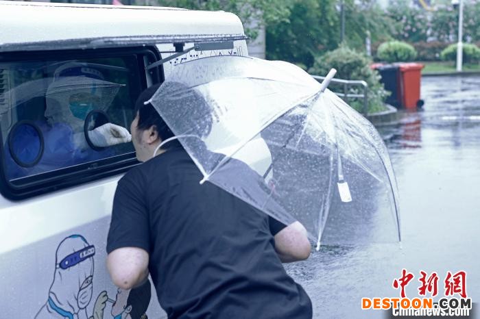 市民正在核酸检测车外进行核酸采样。 殷立勤 摄