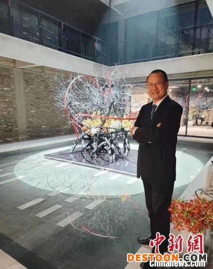 图为蔡冠深站在文化交流中心的艺术品前。 主办方供图