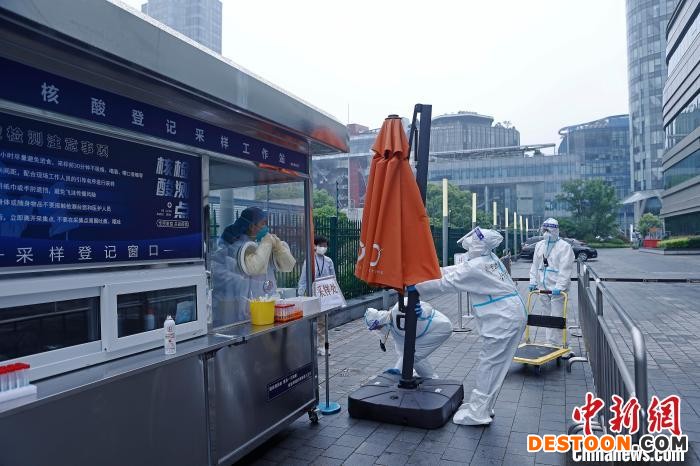 在北外滩核酸检测便民采样点，工作人员正在将大型雨伞安装到位。 殷立勤 摄