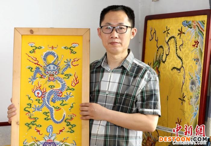 郭庆生与他的作品《海水江崖平针打籽云龙纹图》。 吕明会 摄
