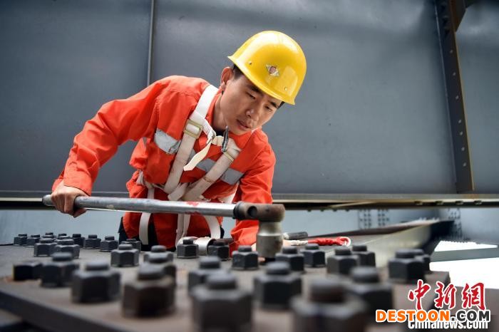 图为管魁更攀爬至钢梁上对高强度螺栓进行更换。 黄旸 摄