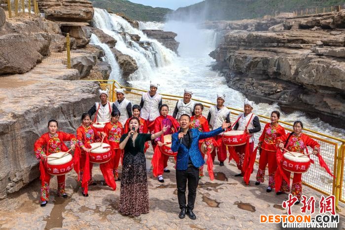 图为演职人员在陕西壶口瀑布前为游客表演歌曲合唱。 兰华 摄