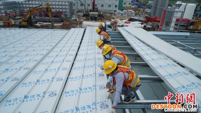 施工现场，劳动者们齐心协力铺设建材。 受访者 供图