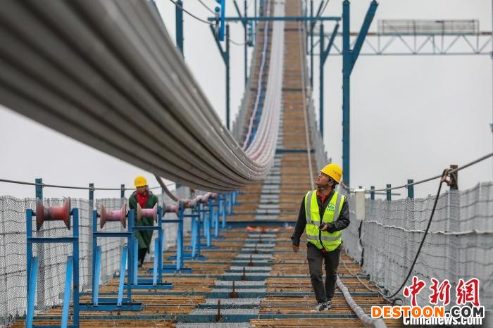 两位工人在大桥猫道上指挥监控索股牵引。 瞿宏伦 摄