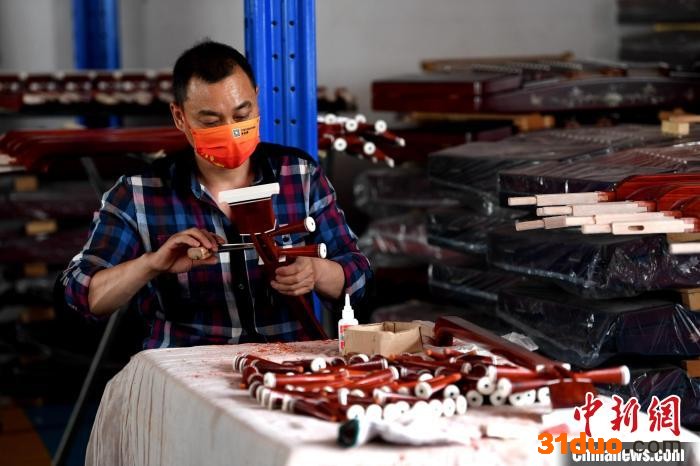 工人为三弦琴杆绞轴。 崔佳栋 摄