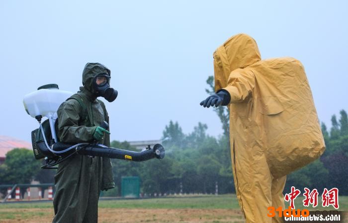 图为演练中身穿绿色防化服的官兵对身穿黄色重型防化服的“染毒人员”进行二次洗消。 蔡霖伟 摄